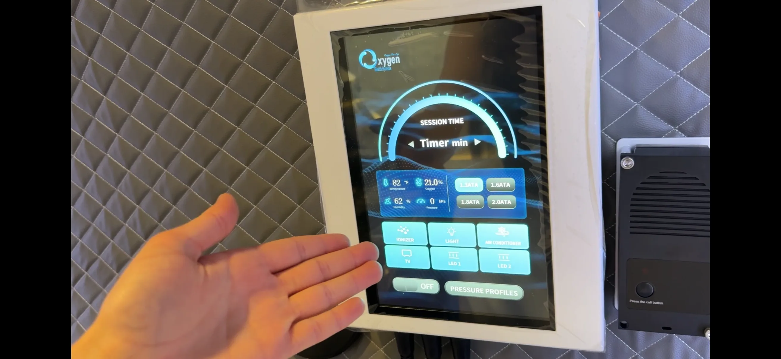 Intuitive high-definition internal touchscreen user interface mounted inside the chamber — showing session timer, real-time temperature, oxygen, humidity and pressure readouts, one-touch ATA pressure selection, and chamber controls